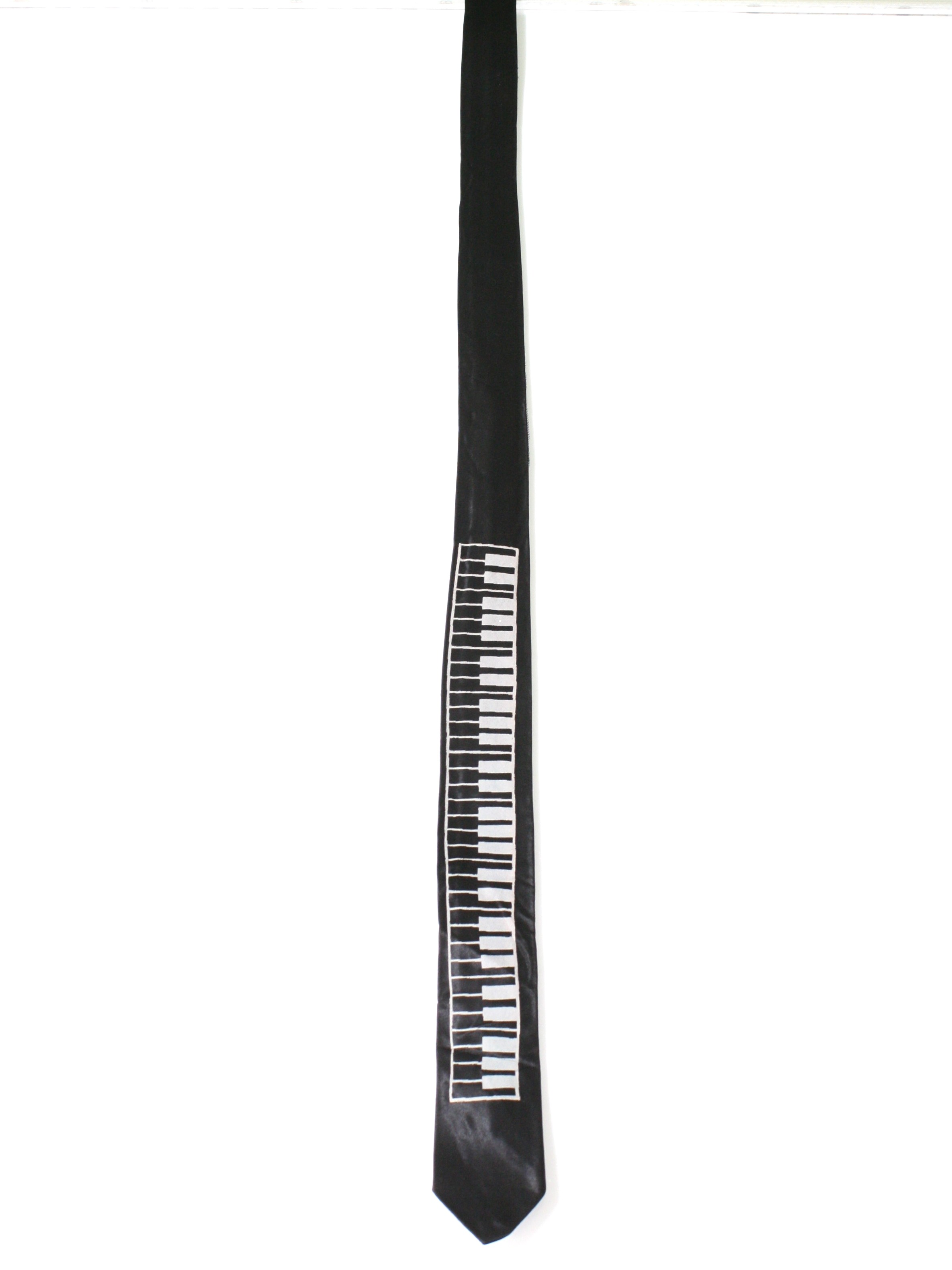1980s Vintage Neck Tie: 80s -Missing Label- Mens black with white piano key acetate blend totally 80s skinny necktie. Tie has pointed ends. Light wrinkling and slight warping of the tie, but